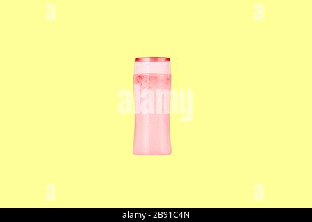 Red plastic bottle with shampoo. Shampoo bottle on a yellow background. Cosmetic product for washing hair and hands without a label Stock Photo