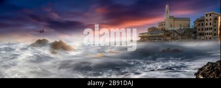 Panorama of the colorful pink sunset over Boccadasse, Liguria, Italy with rough seas and a view to the ancient stone church on the rocky headland Stock Photo