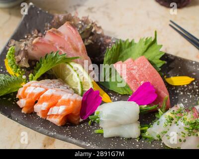 Japanese raw fish on black plate. Also known as Sashimi. Stock Photo