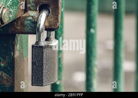 Closed and locked door grill with silver padlock. A metal lock on hinges hangs in close-up on the grate. Security concept or ban, copy space for your Stock Photo