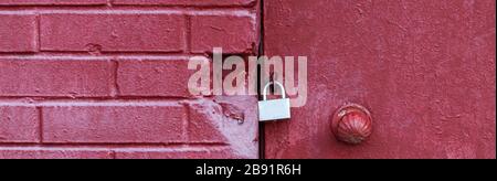 A silver padlock locks the old doors securely. Close- up view. Red brick wall. Copy space for your design Stock Photo