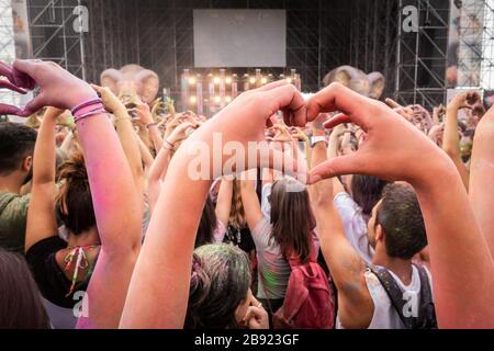 Crowd having party at the concert - Moltitude of people having fun at an event, strobe lights and confetti in the background Stock Photo
