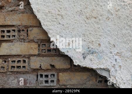Layer of broken plaster over old brick wall. Background texture. Stock Photo