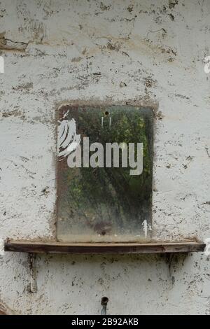 Vintage rusty glass mirror on old textured wall. Stock Photo