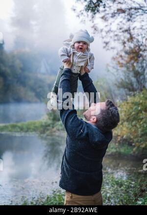 A man is holding a baby near a river Stock Photo