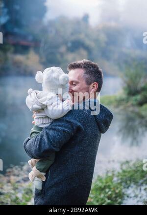 A man is holding a baby near a river Stock Photo