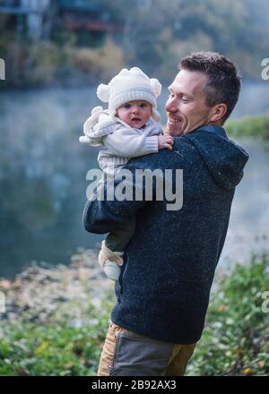 A man is holding a baby near a river Stock Photo