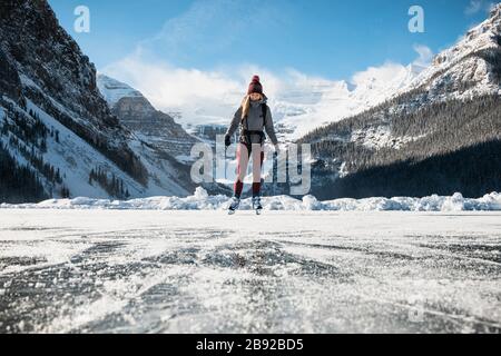 Woman Ice Skating on Frozen Lake at Lake Louse in Banff National Park Stock Photo