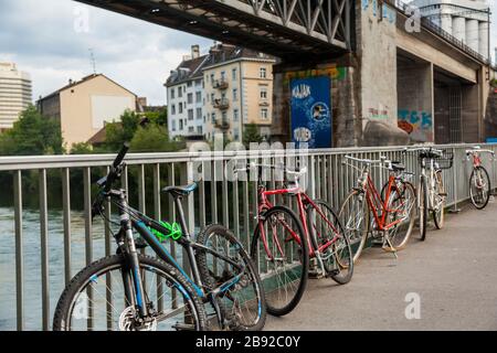 Bicycles locked to the guardrail of a pedestrian bridge (Dammsteg Brücke) over the Limmat River in Zürich, Switzerland near a popular bathing area (Fl Stock Photo