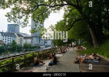 People relax in the shade of trees at a public swimming area (Flussbad Unterer Letten) on the Limmat river in Zürich, Switzerland. Stock Photo