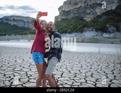 Couple taking a selfie at the edge of a lake during a trip. Stock Photo