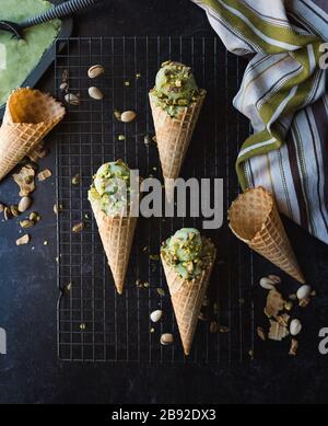 Overhead view of pistachio ice cream in cones on black background. Stock Photo