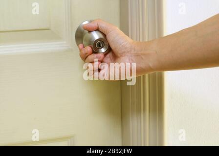 Hand holding steel doorknob closing the door Stock Photo