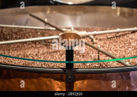 Roasted Coffee Beans Being Mixed in the Mixing Machine, Equipment Working to Prepare Beans for Further Process. Sign Mockup for Logo or Stamp. Stock Photo