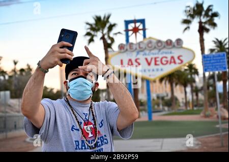 Las Vegas, Nevada, USA. 23rd Mar, 2020. Eddie Sarinana of Las Vegas, wearing a protective face mask, takes a selfie in front of the Welcome to Fabulous Las Vegas sign on March 23, 2020 in Las Vegas, Nevada. Nevada Gov. Steve Sisolak ordered a mandatory shutdown of nonessential businesses in the state until April 16 to help combat the spread of the virus. The World Health Organization declared the coronavirus (COVID-19) a global pandemic on March 11th. Credit: David Becker/ZUMA Wire/Alamy Live News Stock Photo