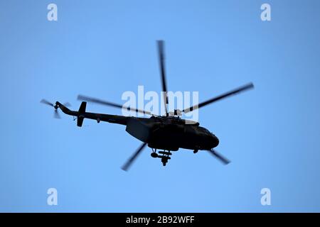 Military helicopter silhouette in flight on background of blue sky. Bottom view, air transportation concept Stock Photo