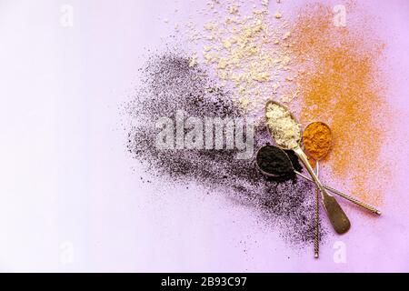 Activated carbon, cocos and curcuma explosion from spoons on a pink background Stock Photo