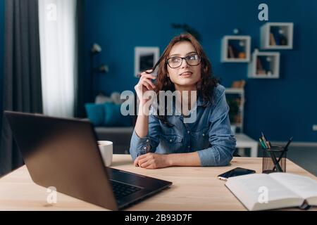 Dreaming girl sitting at home with opened laptop Stock Photo