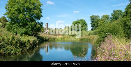 The tower of Wharam Percy church seen across the mill pond of this deserted medieval village in the Yorkshire Wolds Stock Photo