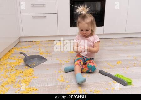 Caucasian child sits on floor at kitchen Stock Photo