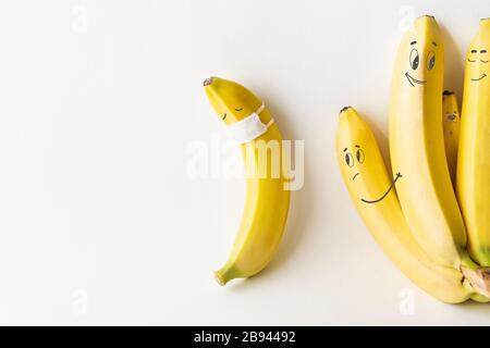 Banana wearing medical mask isolated from the crowd. Conceptual image of social distancing. Stock Photo