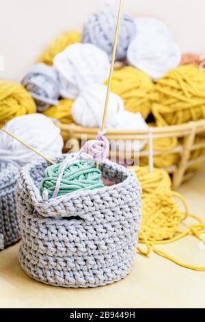 Yellow, white, mustard, gray cotton thread balls and gray knitted basket Stock Photo