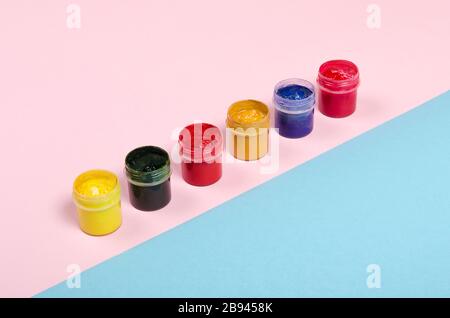 Bottles with paint and brush with colored notepad on pink and blue background Stock Photo
