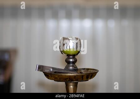 Bowl and head of Syrian hookah made of green apple, with foil on it. After use. Stock Photo