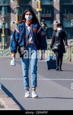 London, UK. 23rd Mar 2020. Westminster Bridge is quieter than usual but is still croosed by a small numbe rof people, some in gloves and masks - Anti Coronavirus (Covid 19) outbreak in London. Credit: Guy Bell/Alamy Live News