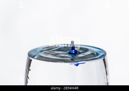 Blue drop splashing into a clear glass of water Stock Photo