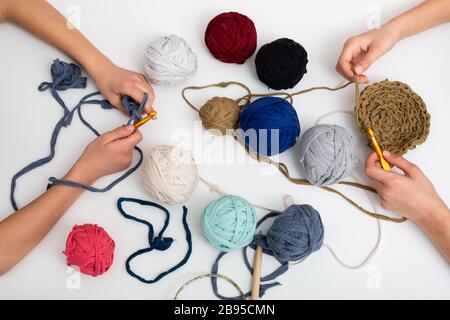 Different colored balls of yarn. Children's hands are crocheted and thread view frome above Stock Photo