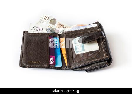 An open brown leather fold-over wallet containing £10 and £20 British banknotes and credit cards Stock Photo
