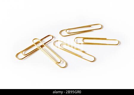 Five large gold-coloured paper clips on a white background Stock Photo