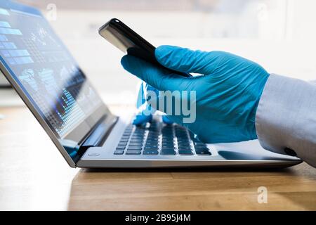 Man In Gloves Protecting From Coronavirus Typing On Computer On Quarantine At Home Stock Photo