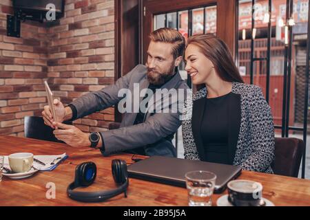 Beautiful young business people are doing selfie using digital tablet and smiling during coffee break Stock Photo