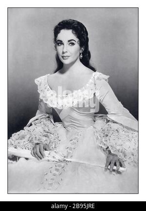 ELIZABETH TAYLOR Archive Hollywood Publicity Still Elizabeth Taylor (1932-2011), British actress, in period costume, holding a closed parasol, in a studio portrait publicity still for 'Raintree County', 1957 a romantic film drama, directed by Edward Dmytryk (19081999), starred Taylor as 'Susanna Drake Shawnessy Stock Photo