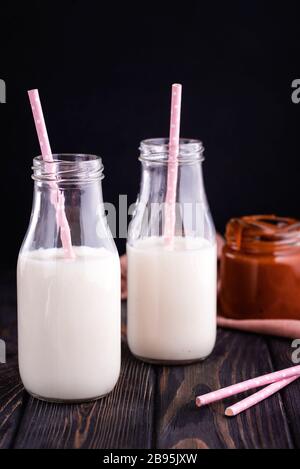 Two glass bottles with fresh milk and tubes on the table. A healthy breakfast Stock Photo