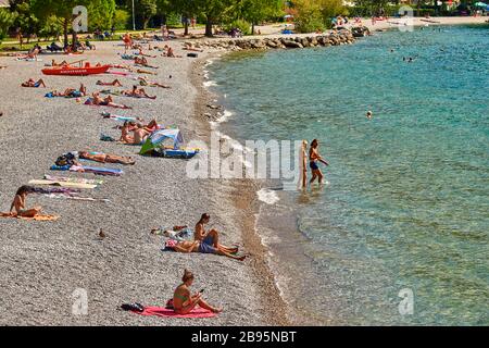 Torbole, Italy-09 October 2018: People sitting at the beach on the lounge chair and admiring Lake Garda in the summer time,View of the beautiful Lake Stock Photo
