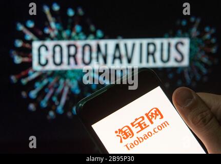 In this photo illustration the Chinese online shopping website owned by Alibaba Group, Taobao, logo seen displayed on a smartphone with a computer model of the COVID-19 coronavirus on the background. Stock Photo