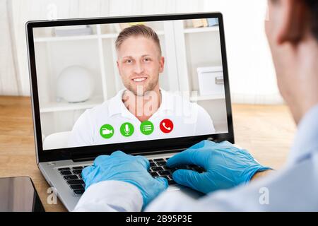 Man In Gloves On Coronavirus Quarantine Having Video Conference With Doctor Stock Photo
