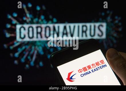 In this photo illustration the China Eastern airline logo seen displayed on a smartphone with a computer model of the COVID-19 coronavirus on the background. Stock Photo