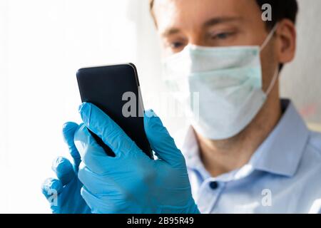 Man In Mask And Gloves Using Mobile Phone On Coronavirus Quarantine Stock Photo