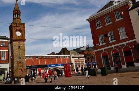 Customers queue outside the Santander bank in Ormskirk town centre.  Other people are wearing face masks as they go about town because of coronavirus. Stock Photo