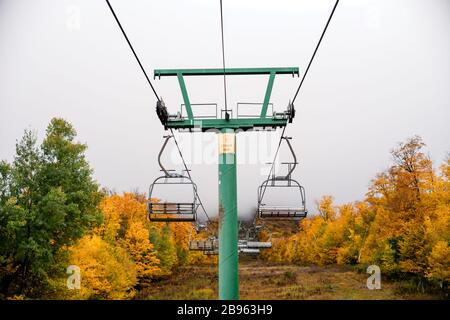 Vacant chairlift at ski resort during peak autumn foliage in Vermont. Stock Photo