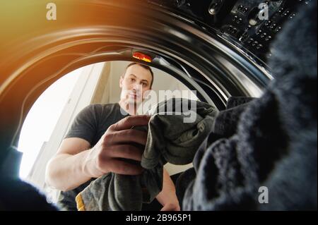 Man holding dirty cloth in hand view inside of washing machine Stock Photo