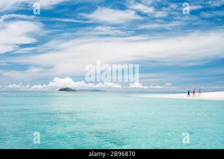 People walk around on a remote sandbar during low tide in Fiji. Stock Photo