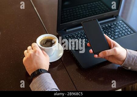 Remote work. Man using laptop, holding smart phone for business work or study in smart watch drink coffee. Freelancer work space. Close up remote work Stock Photo