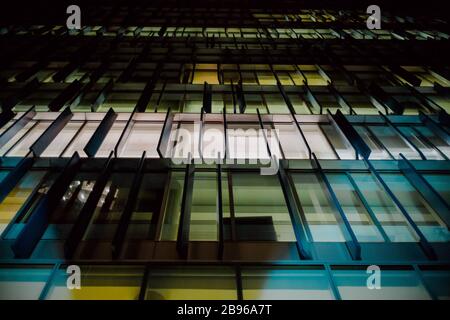 Colorful windows illuminated in a contemporary commercial building at night. Stock Photo