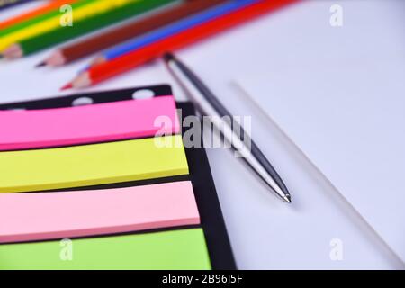 Metal pen and multi-colored blank stickers close-up on the office desk on a white background Stock Photo