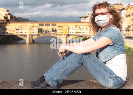COVID-19 coronavirus in Italy, young woman in face medical mask in Florence street. Tourist landmarks closed due to corona virus outbreak. Stock Photo